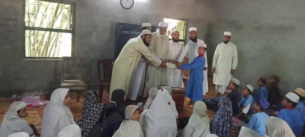 Teachers handing a prize to a student in front of the classroom