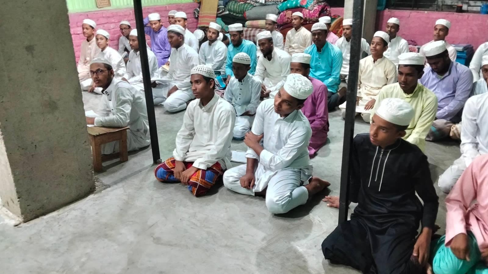 Older students listening during an assembly in the madrasa hall